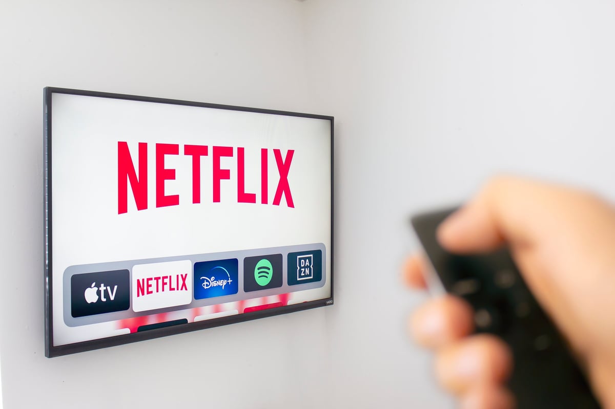 A person holding an Apple TV remote using the Netflix app, illustrating how streaming taught audiences to recognise a brand by its sound.