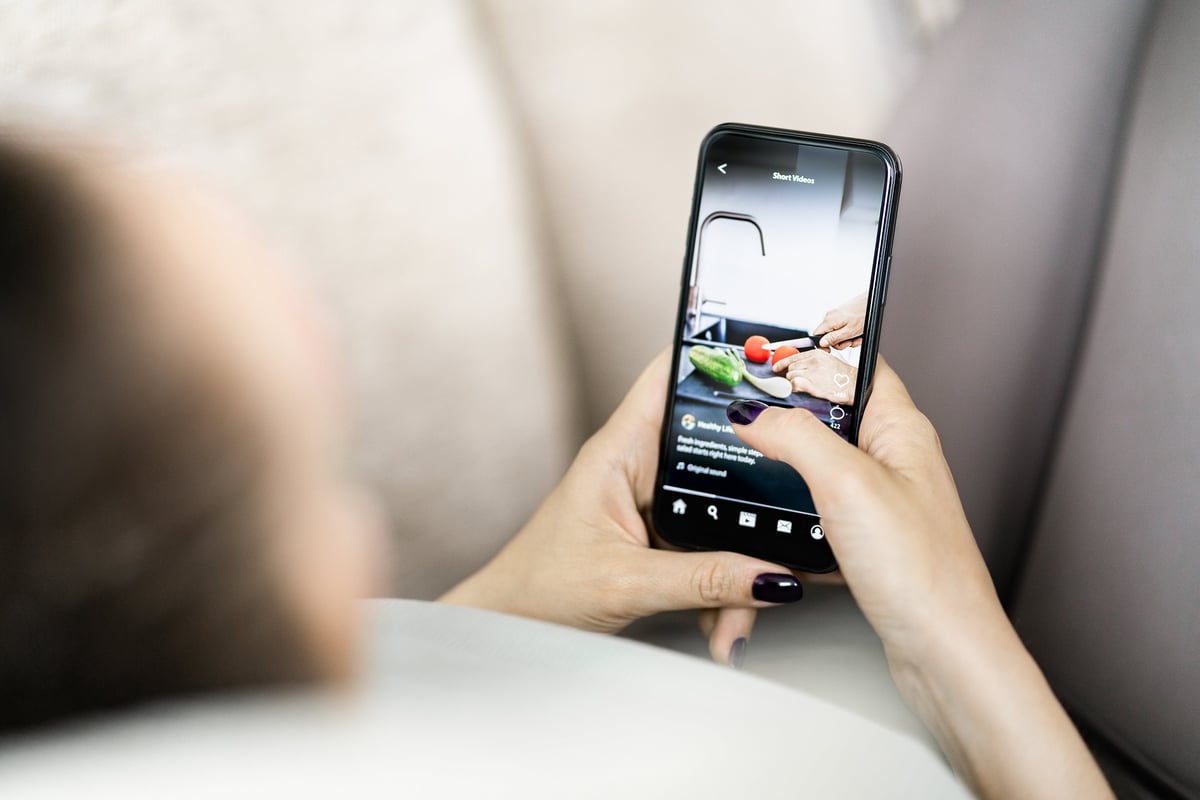 Hand holding a phone showing a social media feed, illustrating a scroll-stopping ad.