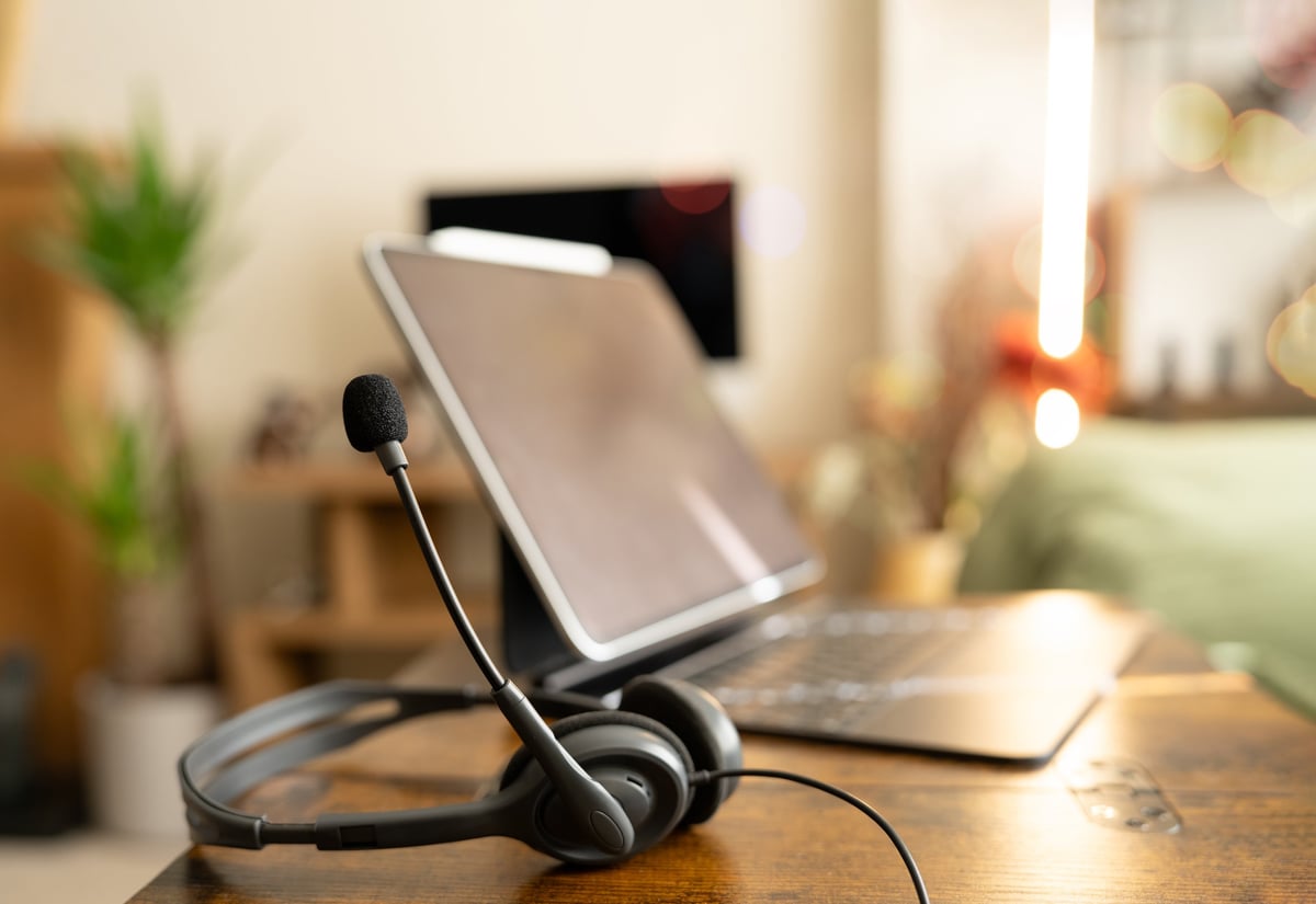 Laptop and headset on a desk in a home office, representing content that ranks on Google and gets quoted by AI.