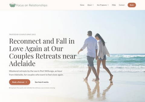 Couple walking on beach holding hands with ocean waves in background, couples retreat website header