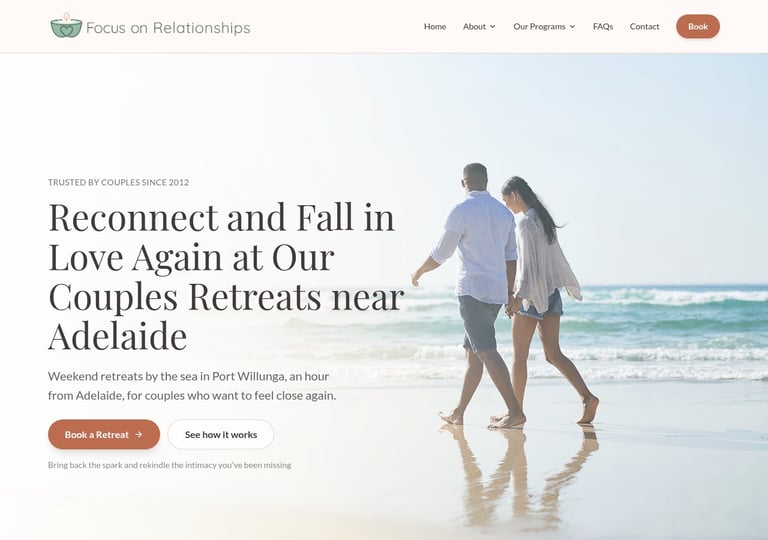Couple walking on beach holding hands with ocean waves in background, couples retreat website header