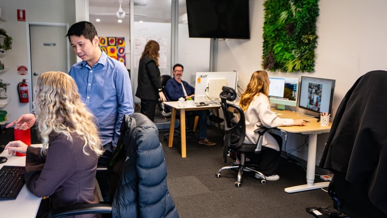 Modern office workspace with multiple employees working at desks and collaborating